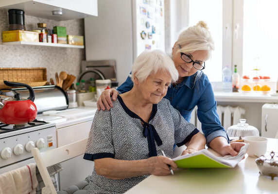 Mature woman helping elderly mother with paperwork.